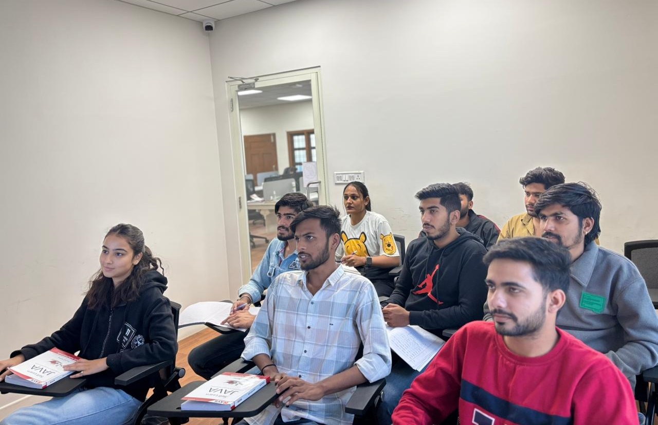 Students with Java textbooks listening attentively during a classroom lecture at Rays EdTech